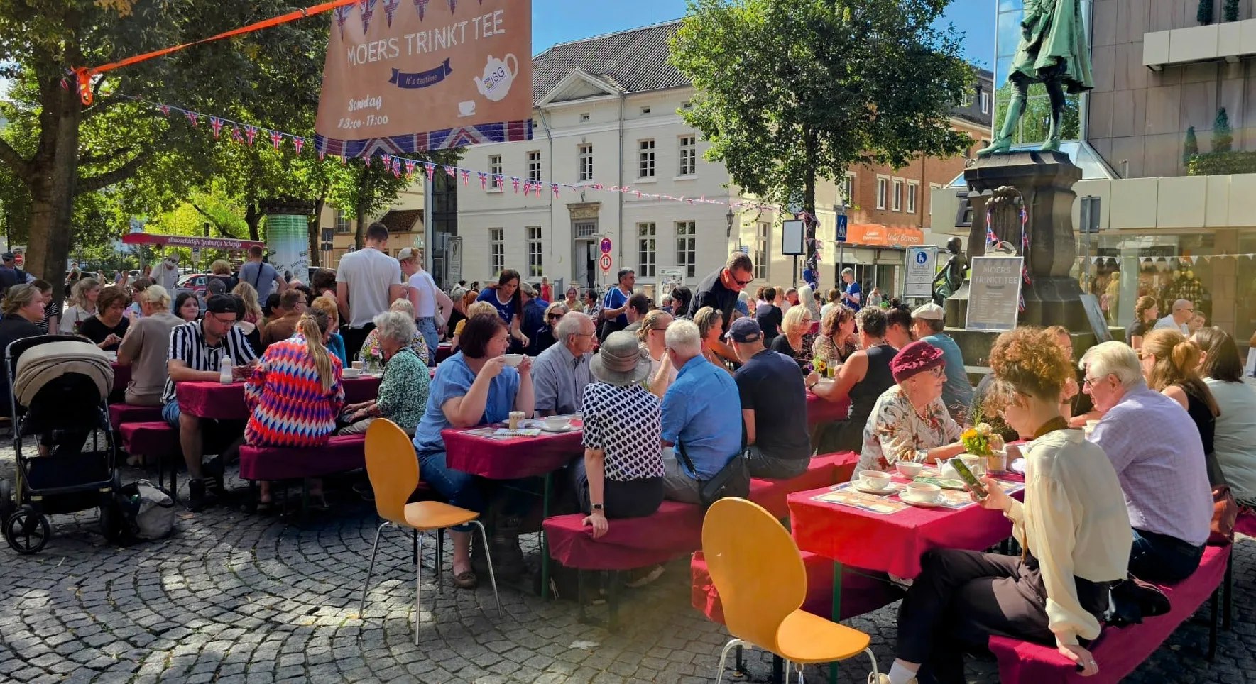Viele Menschen sitzen gemeinsam an den langen Teetafeln in Moers.