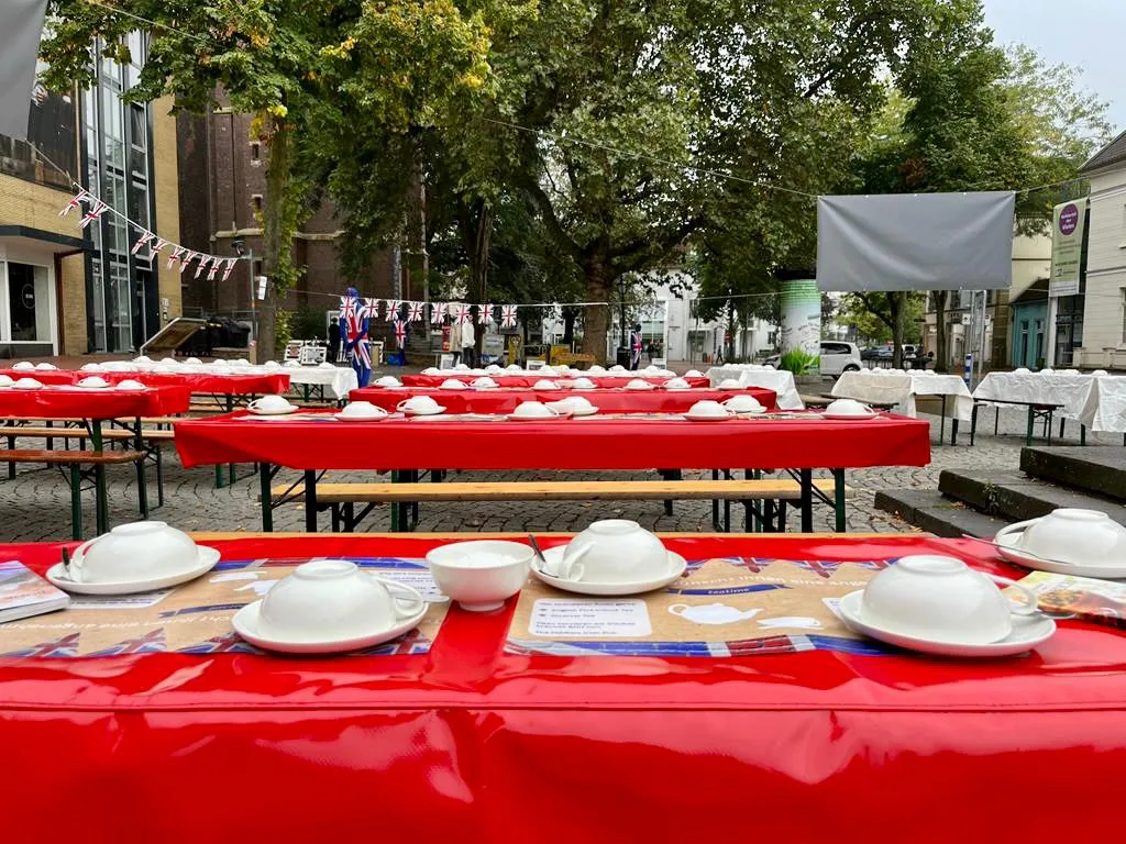 Eine lange rote Tafel mit weißem Porzellan kurz vor Beginn der Teatime.